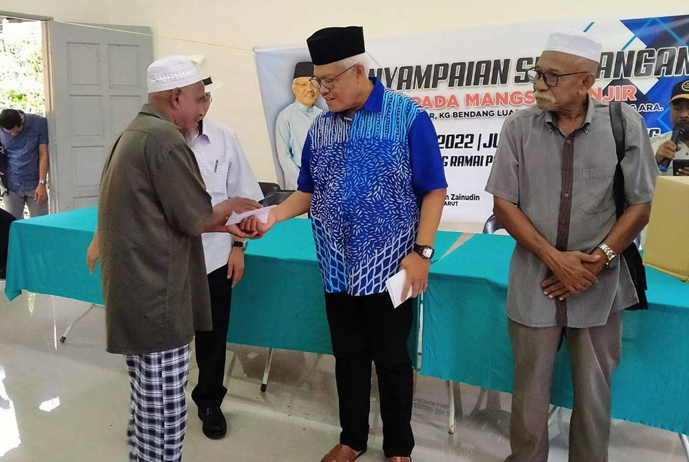 Hamzah (dua dari kanan) menyampaikan sumbangan kepada mangsa banjir di Dewan Orang Ramai Kampung Pantai Besar Ulu, Ijok pada Jumaat.