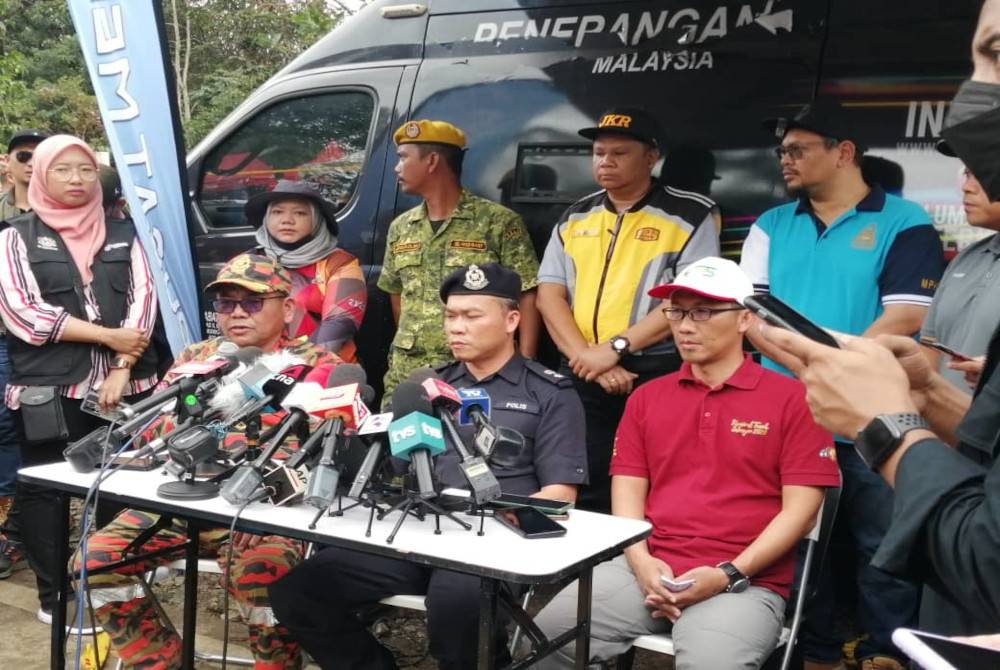 Norazam (duduk, kiri) pada sidang akhbar di lokasi di tanah runtuh di tapak perkhemahan Father’s Organic Farm, Batang Kali pada Sabtu.