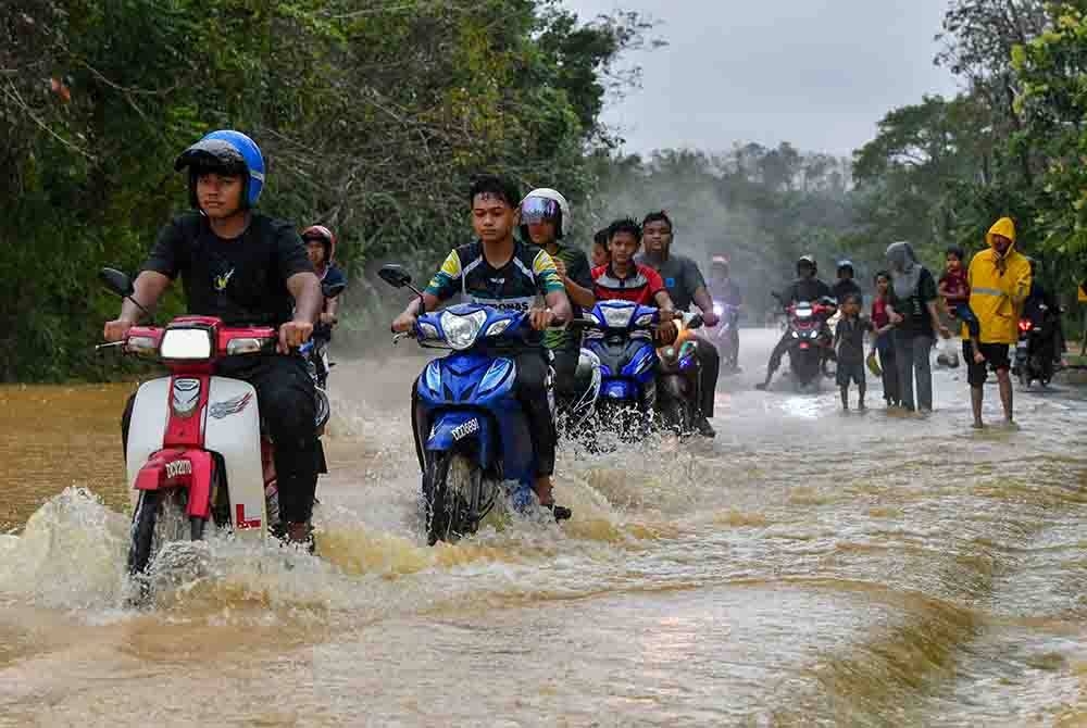 Penunggang motosikal meredah laluan Jalan Kampung Bukit Langsat-Bukit Sireh yang dinaiki air ekoran hujan lebat berterusan sejak Sabtu. -Foto: Bernama.