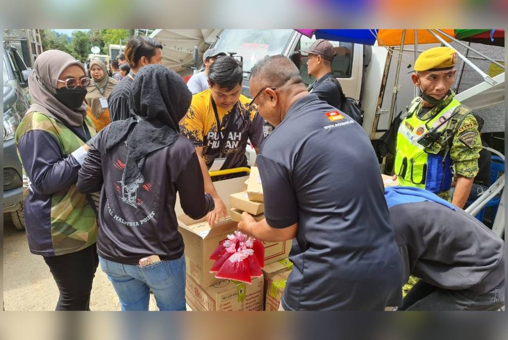 Kakitangan Rumah Hutan Terapi Alam mengagihkan makanan kepada pasukan keselamatan dan petugas media di lokasi tragedi Jalan Genting - Batang Kali, pada Ahad.