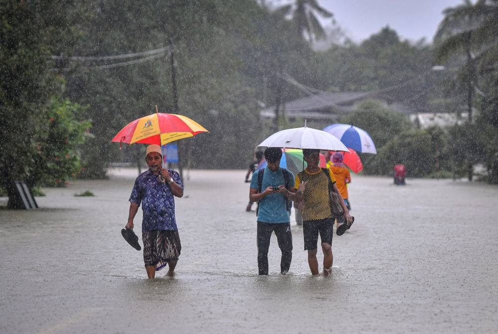 Beberapa penduduk mengharungi air banjir ketika tinjauan di Kampung Tengkawan, Kuala Berang, Terengganu pada Ahad. - Foto Bernama