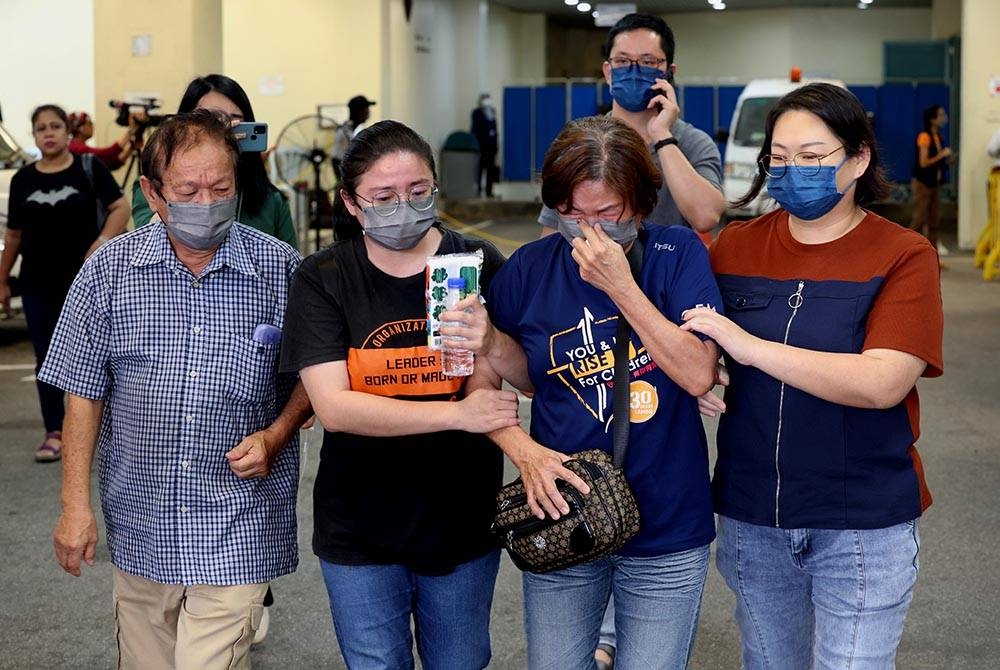 Seorang ibu Beh Su Lee, 59, (dua dari kanan) hampir rebah ketika meninggalkan Jabatan Forensik Hospital Sungai Buloh di sini hari ini selepas menuntut mayat empat ahli keluarganya. Foto Bernama