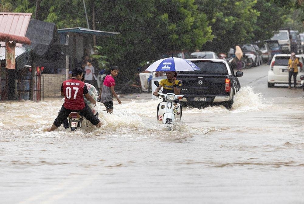 Beberapa kenderaan meredah jalan yang dinaiki air berikutan hujan lebat di Kampung Kubang Kual, Rantau Panjang, Kelantan pada Ahad. - Foto Bernama