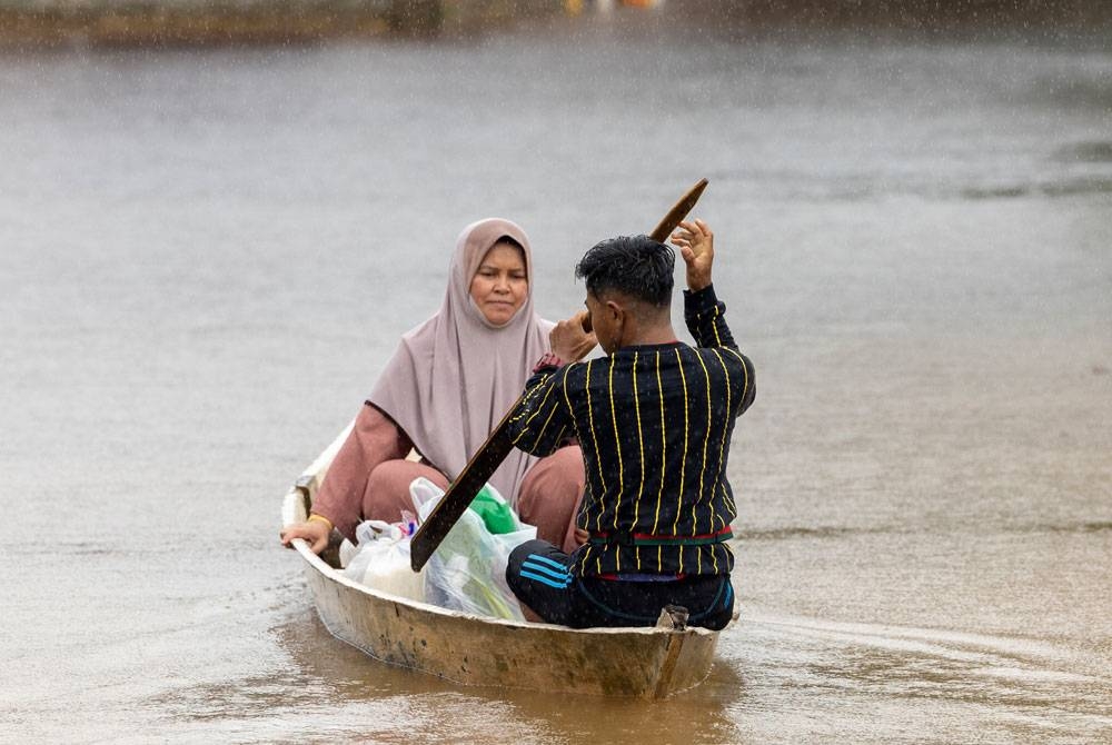 Kelihatan penduduk Kampung Kusar Gual Periuk, Rantau Panjang, menaiki perahu meredah banjir untuk membeli bekalan makanan harian keluarganya ketika tinjauan Bernama. - Foto Bernama