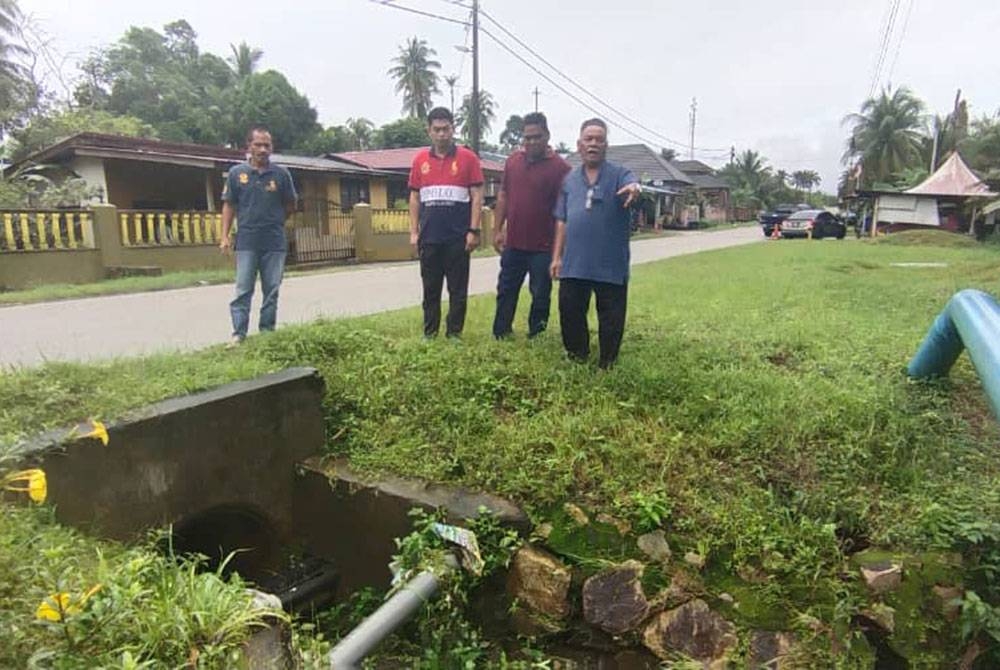 Wan Ismail (kanan) menunjukkan longkang dan pembetung berhampiran rumahnya yang didakwa menjadi punca kejadian banjir kilat sering berlaku itu kawasan itu termasuk yang terbaharu pada malam Ahad.