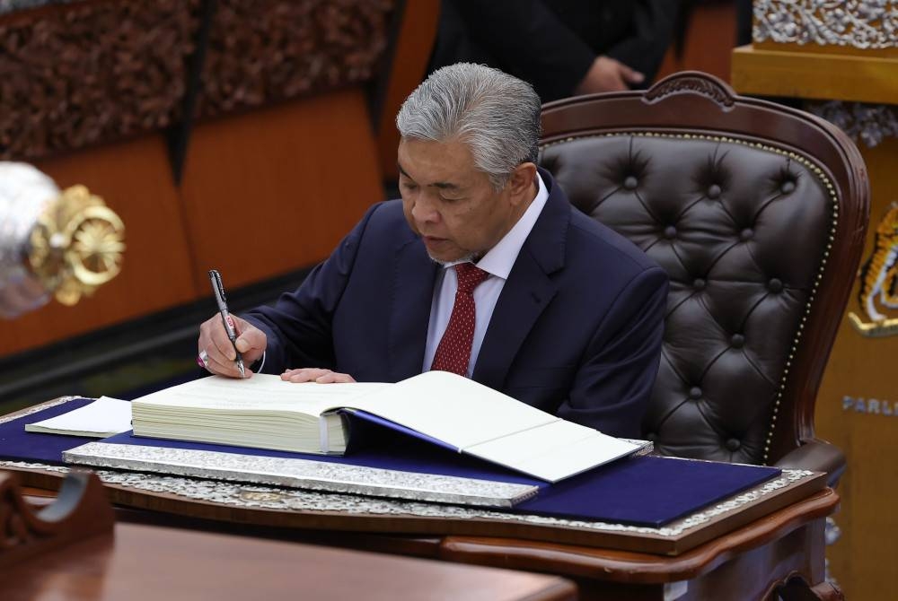 Ahmad Zahid menandatangani watikah pelantikan selepas mengangkat sumpah sebagai ahli Parlimen pada Mesyuarat Pertama Penggal Pertama Parlimen ke-15 di Bangunan Parlimen hari ini. - Foto Bernama