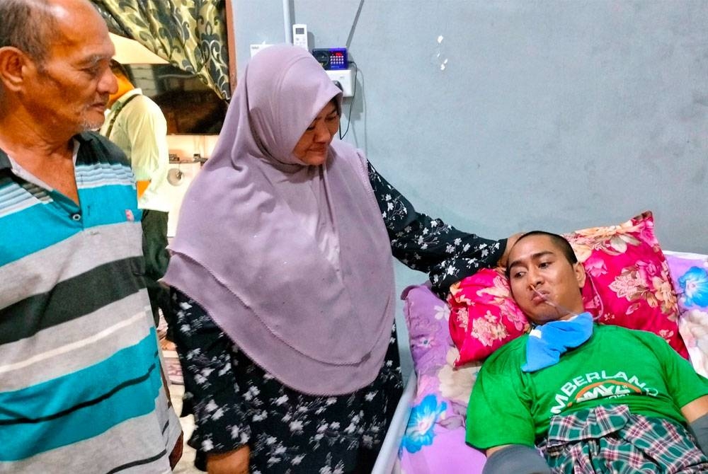 Faridah (dua,kiri) dan suaminya sedih mengenangkan keadaan anak mereka Muhammad Haikal ketika menerima kunjungan Skuad Prihatin Perkeso Melaka di Kampung Kuala Sungga di Tebong, di sini, pada Selasa.