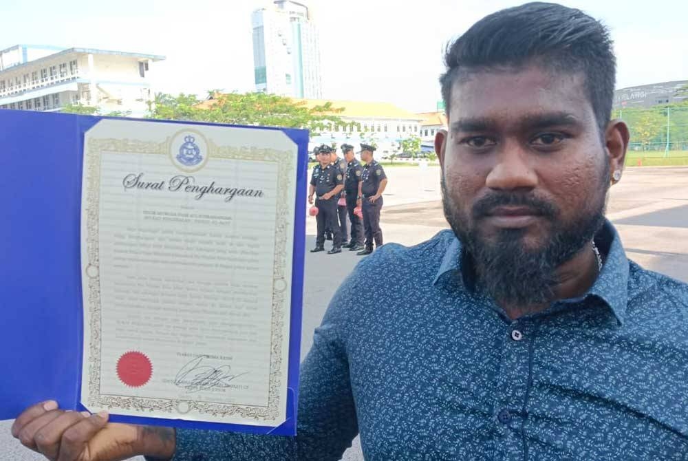 Muruga menunjukkan sijil penghargaan yang diterimanya dalam Majlis Perhimpunan Bulan Disember 2022 di Dataran Kawad, IPK Johor, Johor Bahru pada Selasa.