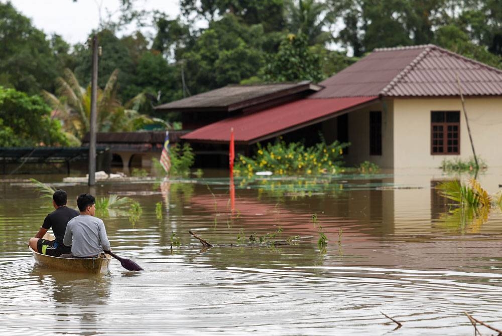 Beberapa penduduk kampung di Pasir Mas menaiki sampan untuk meninjau keadaan rumah mereka. - Foto: Bernama