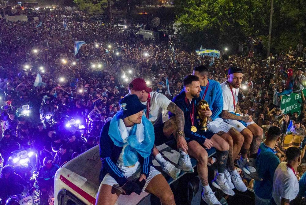 Messi (tengah) bersama beberapa pemain Argentina duduk di atas bumbung sebuah bas ketika perarakan di Buenos Aires pada petang Rabu.