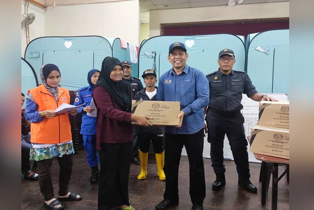 Saharuddin (dua dari kanan) menyampaikan sumbangan makanan kepada mangsa banjir si PPS Dewan Sivik Bukit Payong, Marang.