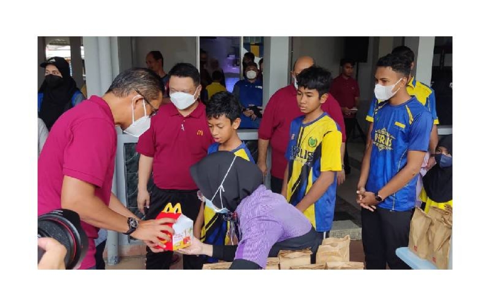 Raja Muda Perlis, Tuanku Syed Faizuddin Putra Tuanku Syed Sirajuddin Jamalullail bersama Pengarah Urusan dan Rakan Operasi Tempatan McDonald’s Malaysia, Datuk Azmir Jaafar (kiri) menyerahkan sumbangan makanan kepada pelajar sekolah rendah dari Perlis yang menerima Pek Kembali ke Sekolah.