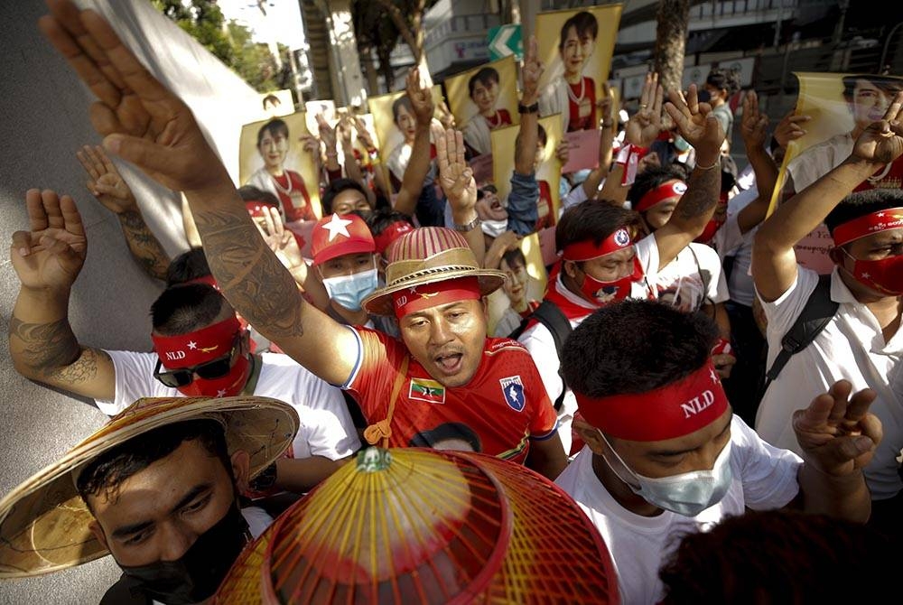 Pekerja migran Myanmar yang tinggal di Thailand menunjukkan tabik hormat tiga jari sambil memegang gambar ikon demokrasi Myanmar Aung San Suu Kyi pada perhimpunan di luar kedutaan Myanmar di Bangkok, Thailand, pada Isnin. - Foto EPA