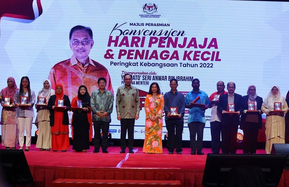 Anwar (tujuh dari kiri) dan Ewon (enam dari kiri) bergambar bersama sebahagian penerima Anugerah Kecemerlangan Peserta Program Pemantapan Penjaja dan Peniaga Kecil pada Majlis Perasmian Konvensyen HPPK2022 di Pusat Konvensyen Antarabangsa Putrajaya pada Khamis - Foto Bernama.
