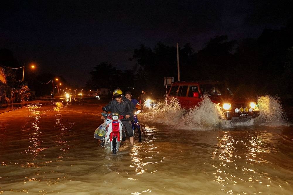 Kenderaan mengharungi air banjir berhampiran Sungai Paka yang mulai surut di Jalan utama Dungun - Kuala Terengganu berhampiran Kampung Nyior, Paka pada malam Khamis. - Foto Bernama