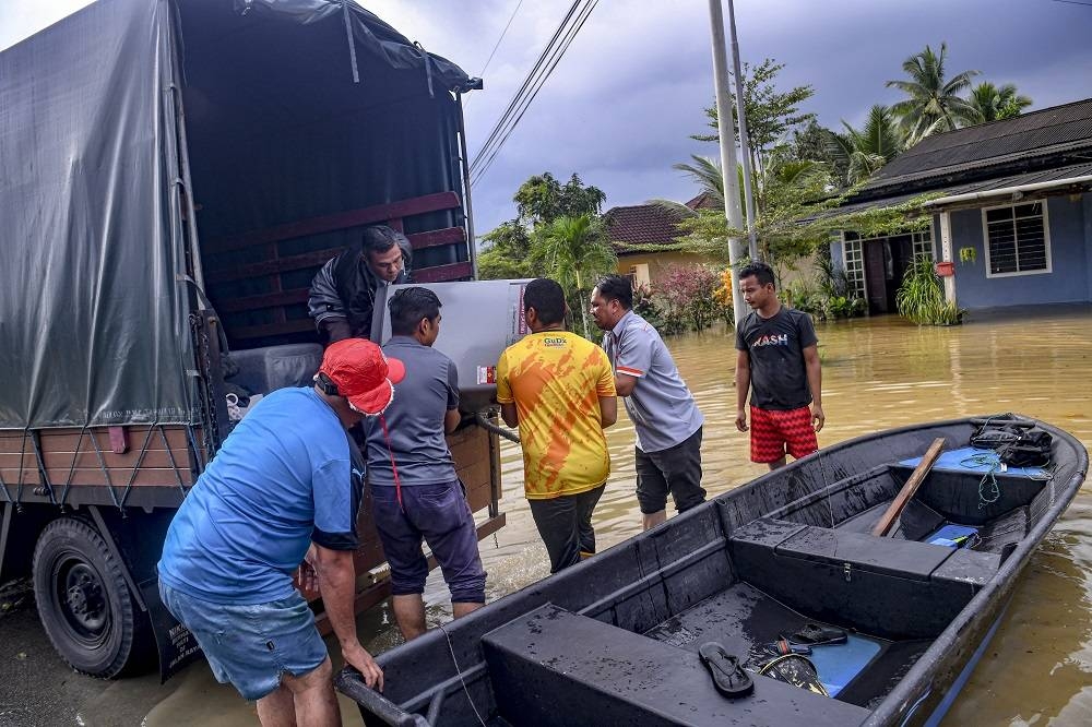 Penduduk bergotong-royong memindahkan barangan elektrik selepas kawasan tersebut dinaiki air berikutan hujan lebat berterusan ketika tinjauan di Kampung Jeram, Kuala Terengganu pada Rabu. - Foto Bernama
