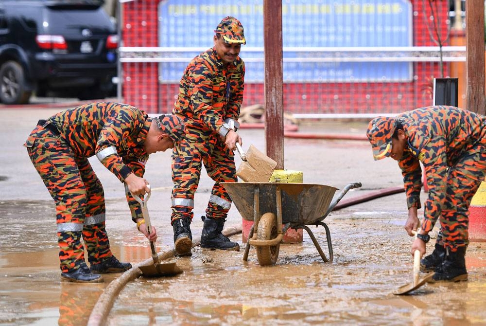 Anggota Jabatan Bomba dan Penyelamat Malaysia Kuala Terengganu bergotong-royong membersihkan lumpur di Sekolah Kebangsaan Pulau Rusa Hilir hari ini selepas dinaiki air dalam kejadian banjir baru-baru ini. - Foto Bernama