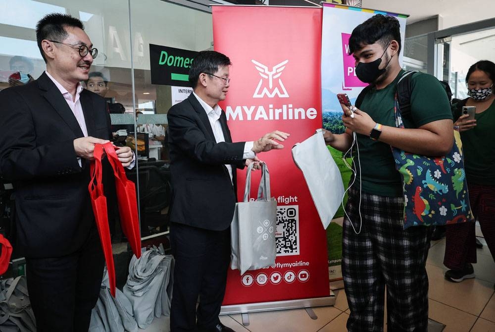 Kon Yeow (dua dari kiri) bersama Ketua Pegawai Eksekutif MYAirline, Rayner Teo (kiri) menyampaikan cenderahati kepada penumpang MYAirline di Lapangan Terbang Antarabangsa Pulau Pinang hari ini. - Foto Bernama