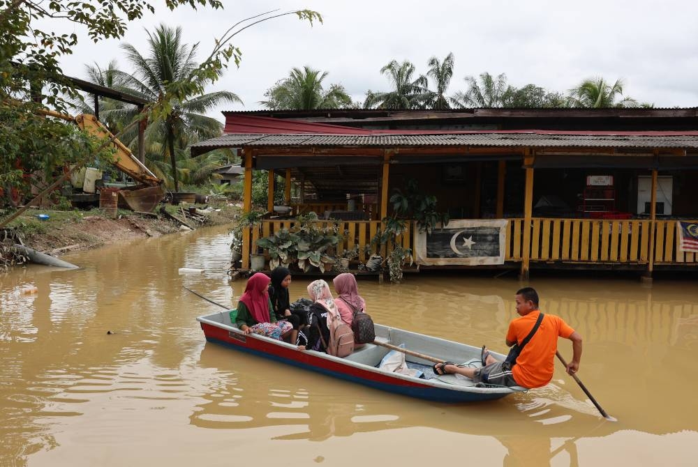 Segelintir mangsa banjir mula kembali ke rumah masing-masing untuk membersihkan perabut dan rumah selepas paras air mulai surut di Kampung Durian Mentangau pada Jumaat. - Foto Bernama