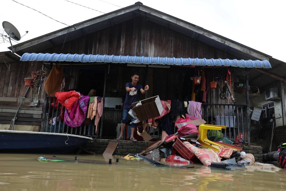 Mangsa banjir mula kembali ke rumah masing-masing untuk membersihkan perabot dan rumah selepas paras air mulai surut di Kampung Durian Mentangau pada Jumaat. - Foto Bernama