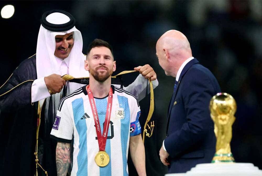 Emir Qatar memakaikan jubah kepada Messi sambil diperhatikan Presiden FIFA, Gianni Infantino ketika majlis penyerahan trofi dan medal Piala Dunia 2022 di Stadium Lusail.