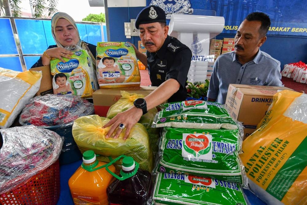 Muhamad Zaki (tengah) melihat bungkusan kit makanan yang disumbangkan oleh Pengurus Besar Econsave, Toh Sharin (kiri) dan Wakil Penyelaras Sektor Korporat ATP Food Malaysia, Azmi Mohamed (kanan) kepada PDRM Kontinjen Kelantan untuk diagihkan kepada mangsa banjir. - Foto Bernama