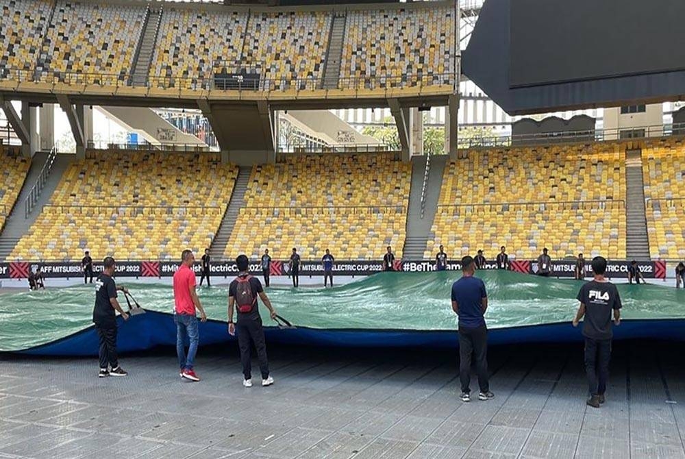 Beberapa orang pekerja menarik kanvas bagi menutup permukaan padang di Stadium Nasional Bukit Jalil. -
Foto FB FAM