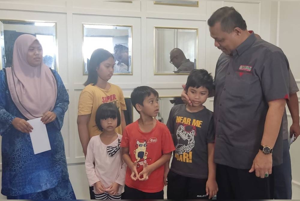 Aimi (kanan) menyantuni anak-anak arwah Amirul Fariz di Yan pada petang Jumaat.