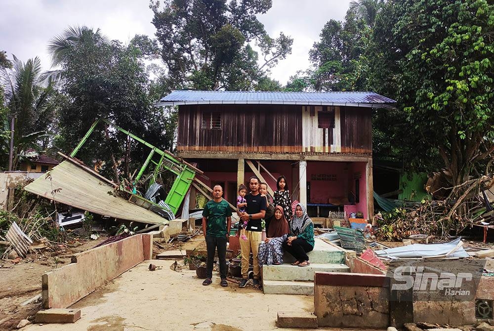 Mek Mas bersama anak dan cucunya di tapak rumah yang hilang dibawa arus kuat dalam kejadian banjir besar pada Ahad lalu.