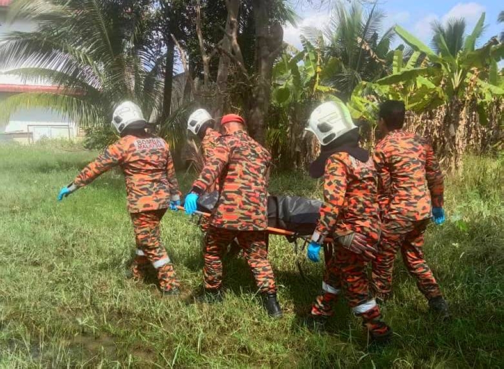 Anggota bomba membawa mayat seorang lelaki yang ditemukan terapung dalam tali air di Kampung Kubang Khacang, Kota Bharu pada Sabtu.