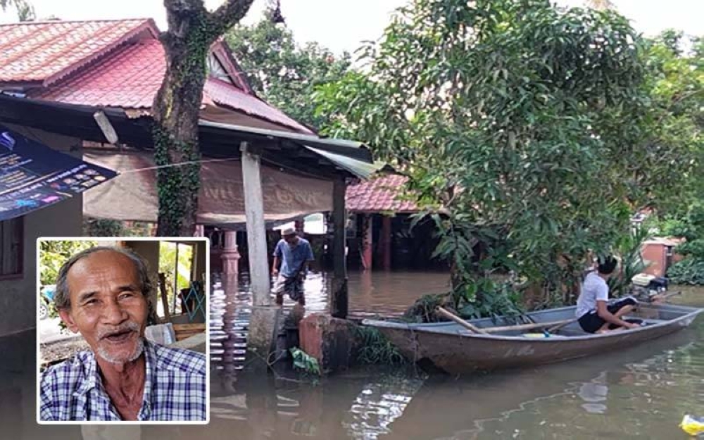 Nasir (kiri) mengharung banjir di pekarangan rumahnya di Kampung Jejulok, Tumpat.