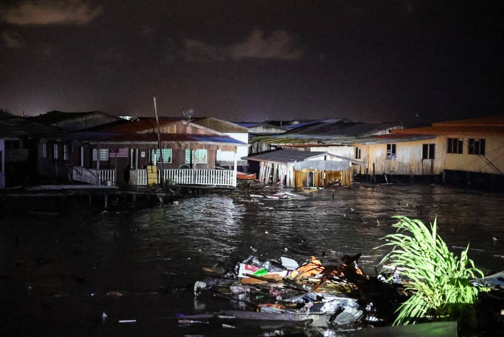 Sebuah rumah mula roboh dipukul ombak akibat fenomena air laut pasang besar di Kampung Forest pada malam Ahad. - Foto Bernama