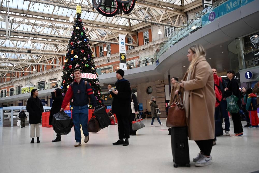 Penumpang menunggu kereta api semasa percutian Ambang Krismas di Stesen Waterloo di London, Britain pada Sabtu. - Foto EPA