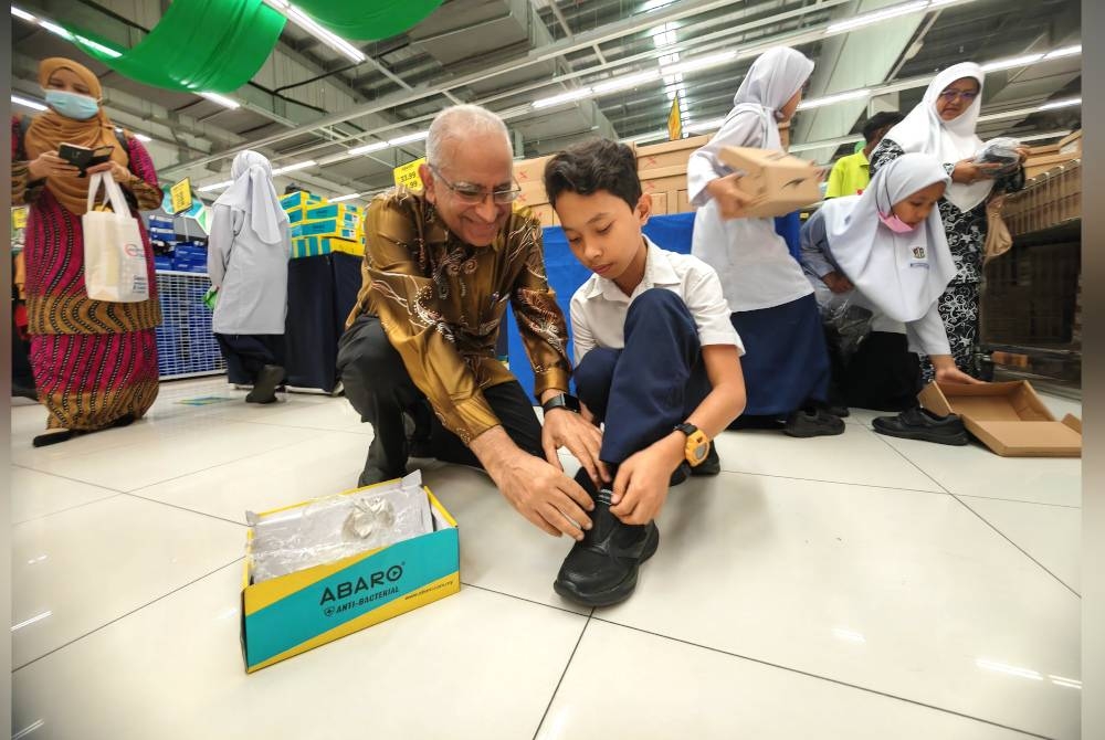 Ahimmat membantu seorang murid mencuba kasut baharu.