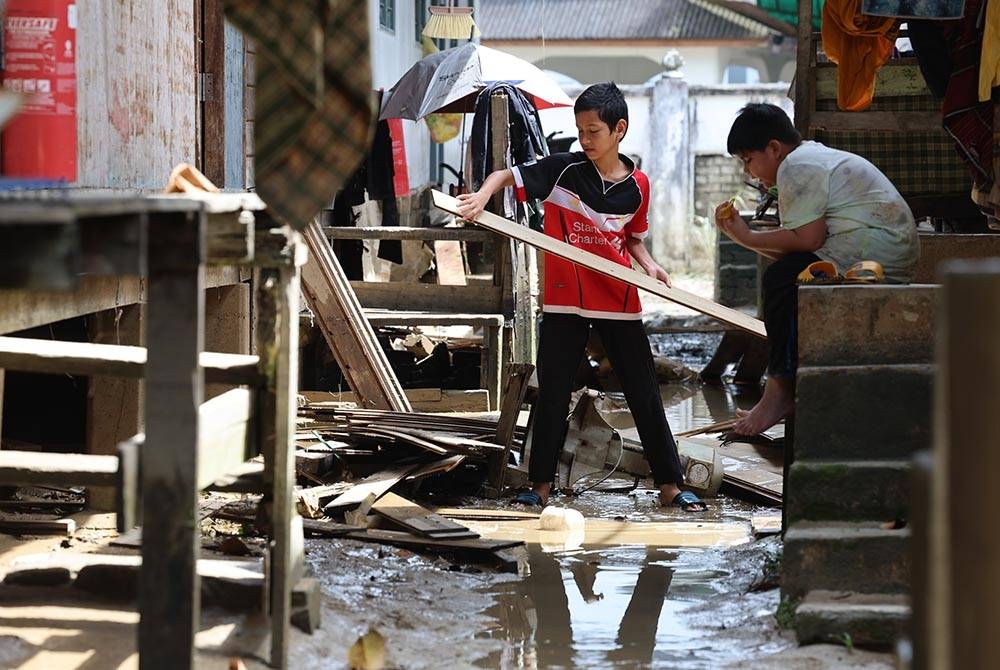 Pelajar tahfiz membersihkan asrama pelajar Madrasah Darul Bayan, Pondok Pinang Merah Paka, Terengganu selepas kawasan berkenaan dinaiki air pada 24 Disember lalu. - Foto Bernama