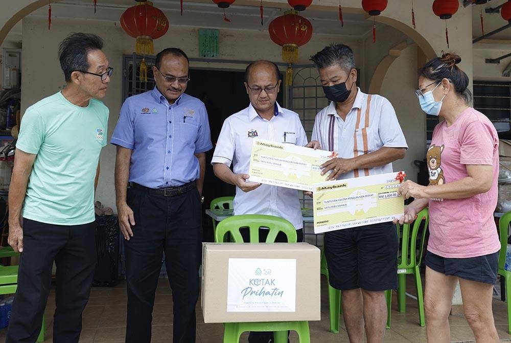 Hee Sem (tengah) menyerahkan replika cek tuntutan faedah pengurusan mayat kepada Hua Keong (dua dari kanan) dan isteri, Chia Eet Loun, 51, (kanan) ketika program Skuad Prihatin Perkeso Melaka di kediaman mereka di Kampung Permai dekat Machap Umboo pada Khamis. - Foto Bernama