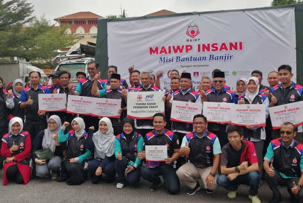 Mohd Daud (berdiri lima dari kanan) bersama peserta konvoi Misi Bantuan Banjir MAIWP Insani pada majlis pelepasan peserta di Kompleks Darul Kifayah pada Rabu.