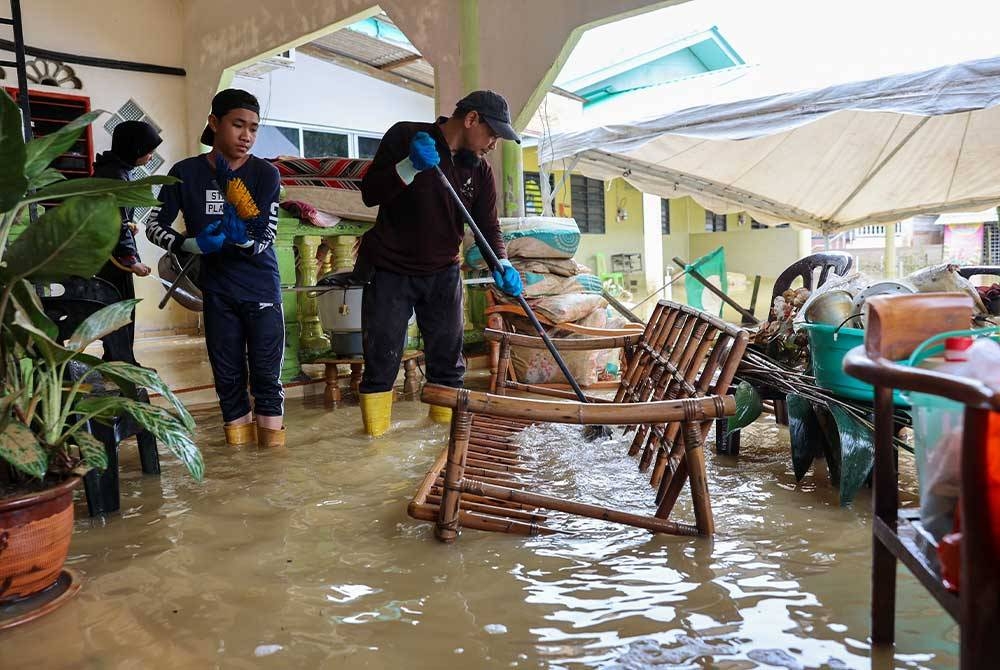 Mangsa banjir kembali ke rumah masing-masing untuk membersihkan rumah. Foto Bernama.