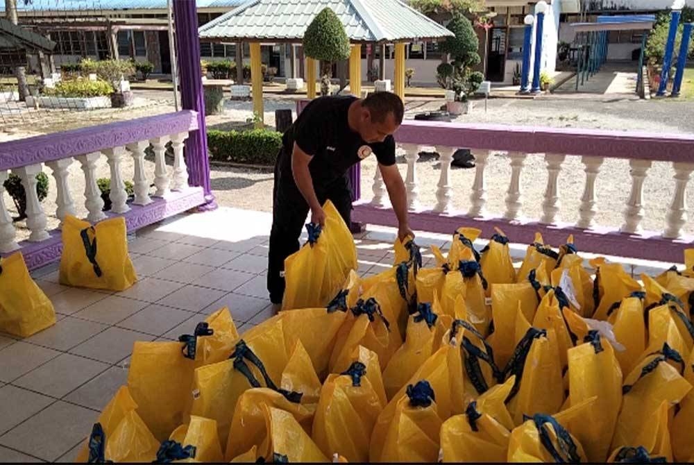 Wan Abu Bakar menyusun pek makanan di Sekolah Menengah Kebangsaan Perempuan Pasir Mas untuk diagihkan kepada mangsa banjir.