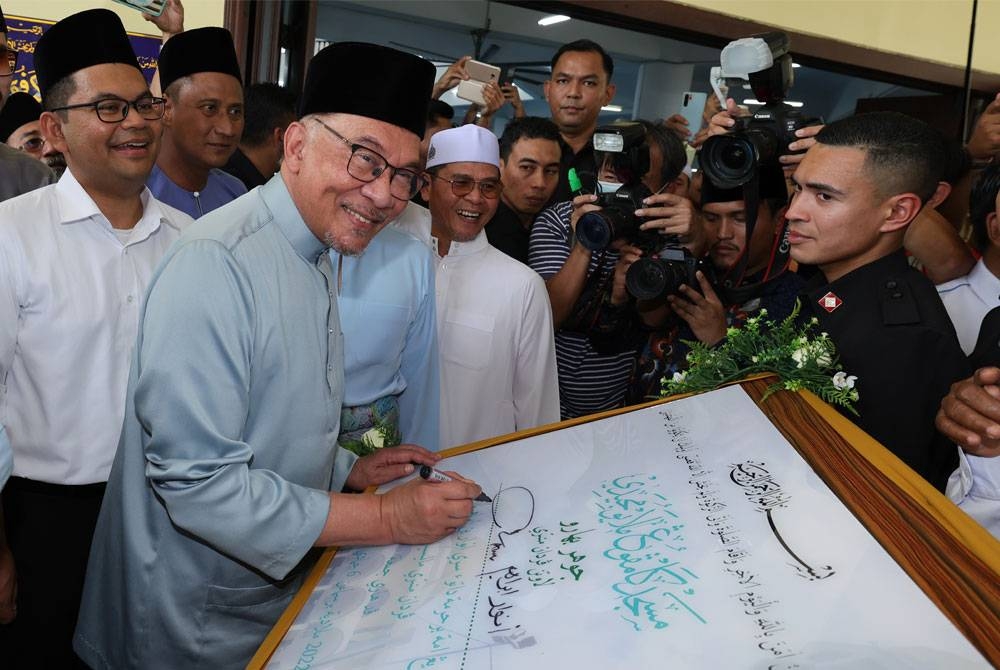 Anwar menandatangani plak Masjid Jamek Kampung Melayu Majidee sempena lawatan kerja di Johor Bahru hari ini. - Foto Bernama