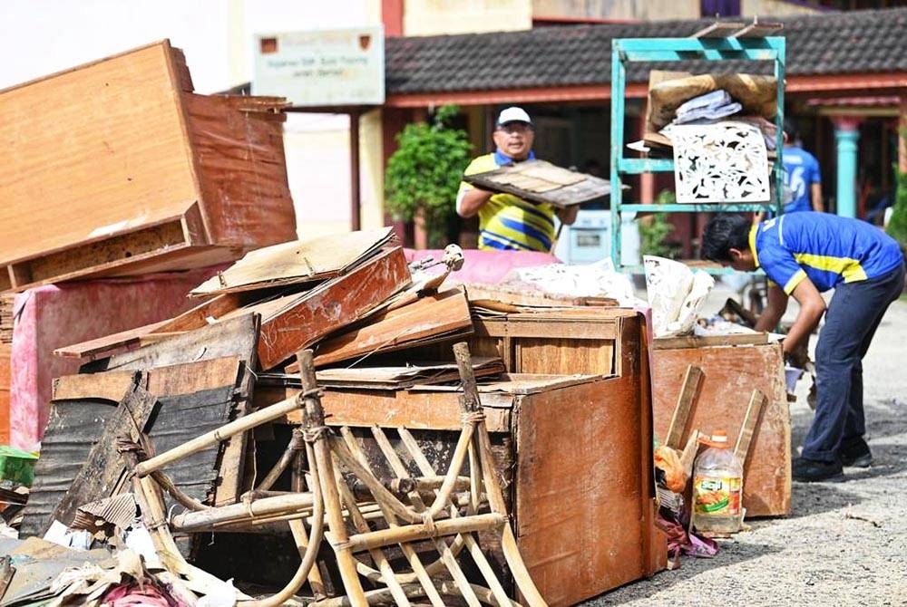 Mohd Fo'ad (kiri) bersama sukarelawan UniMAP membersihkan kawasan sekolah yang terjejas banjir di Terengganu.