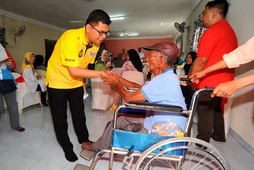 Akmal Nasrullah menyampaikan sumbangan banjir kepada Kamis Sirat dalam program serahan bantuan bencana (banjir) di Balai Raya Jalan Hujung Kampung Melayu Majidee, Johor Bahru pada Sabtu.