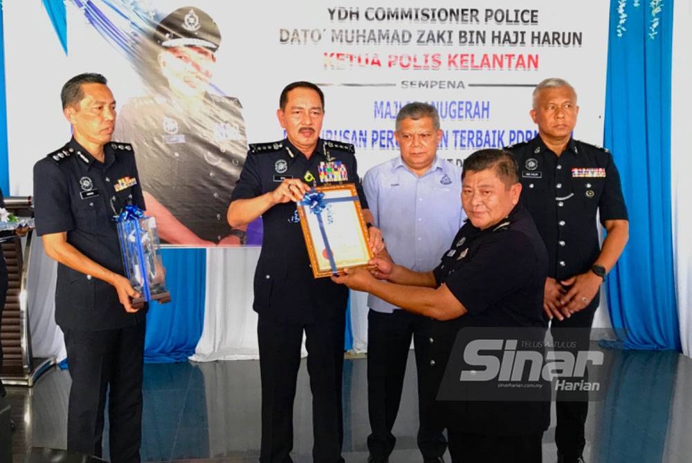 Muhamad Zaki (dua, kiri) menyampaikan sijil penghargaan kepada Mohd Sakri (dua, kanan) di Balai Polis Wakaf Bharu, Tumpat, pada Isnin. Foto SINAR HARIAN