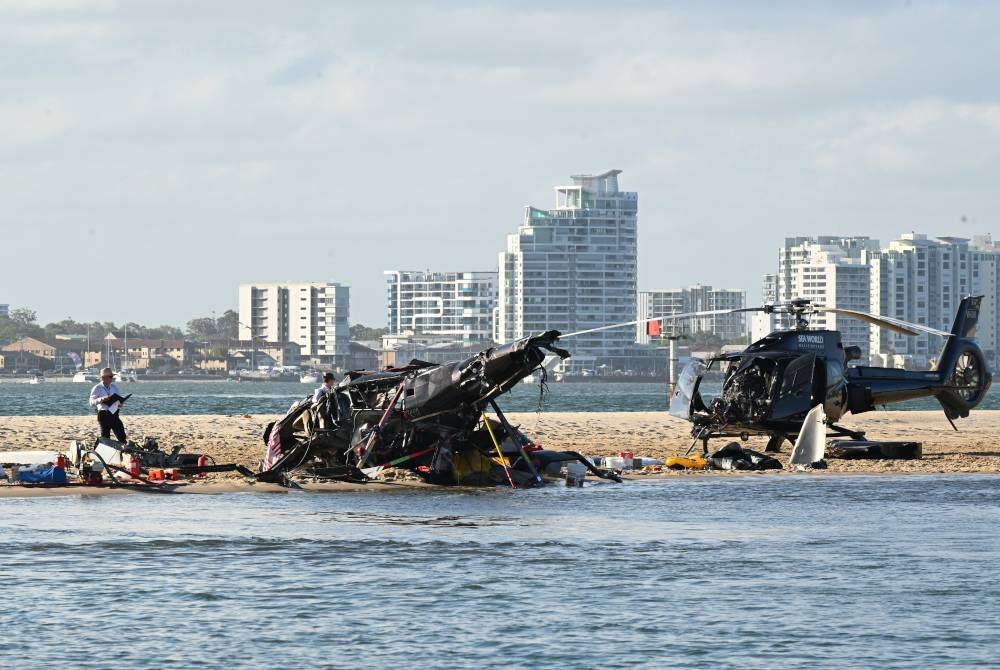 Polis memeriksa sebuah helikopter di tempat kejadian helikopter berlanggar berhampiran Seaworld, di Gold Coast, Australia pada Isnin. - Foto EPA