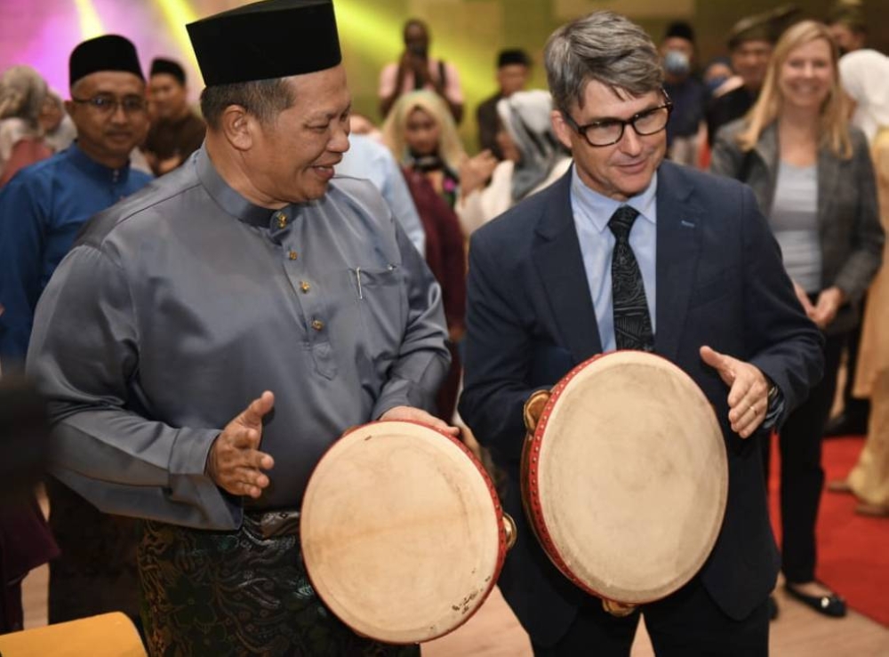 Dr Razli (kiri) MCFreeters (kanan) mencuba memainkan alat muzik tradisional rebana kercing.