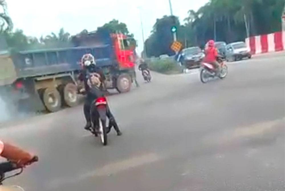 Tangkap layar memaparkan tindakan penunggang motosikal melanggar lampu isyarat merah sebelum nyaris dirempuh sebuah lori di Kampung Acheh, Lumut pada Selasa. - Foto Ihsan pembaca