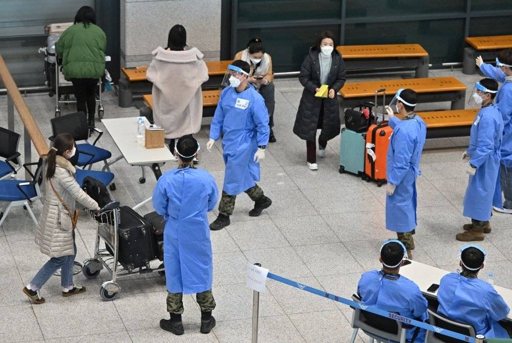 Pengembara dari China yang tiba di Lapangan Terbang Antarabangsa Incheon di Korea Selatan dibawa ke pusat ujian saringan Covid-19. - Foto AFP