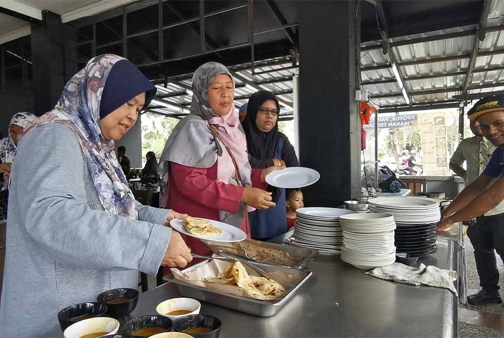 Sebahagian pelanggan yang beratur untuk mengambil hidangan roti canai yang disediakan secara percuma pada pagi Jumaat.