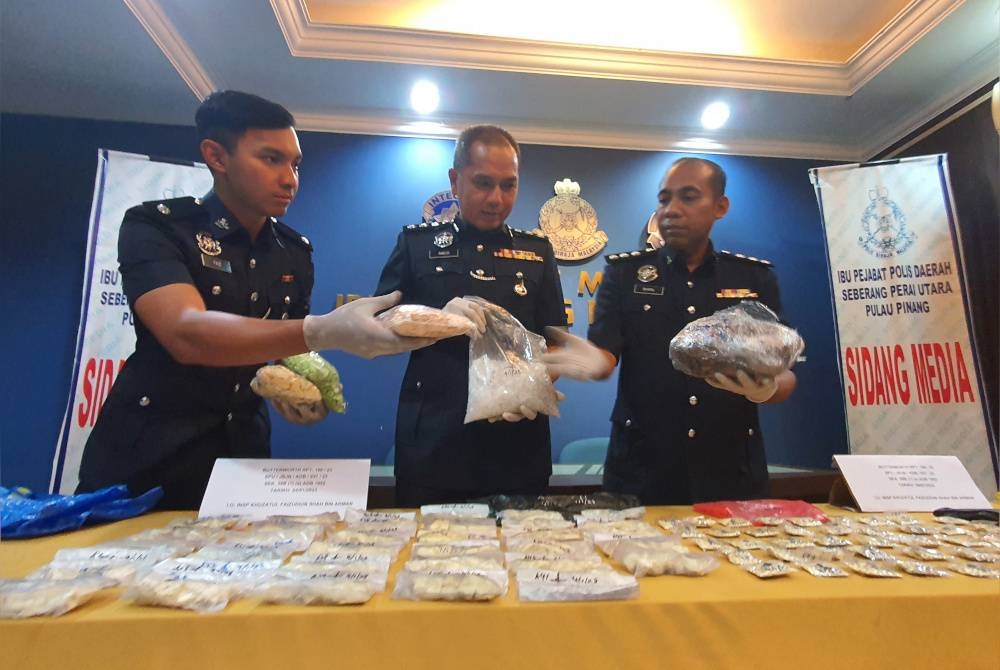 Mohd Radzi (tengah) bersama pegawai siasatan kes menunjukkan dadah yang dirampas.