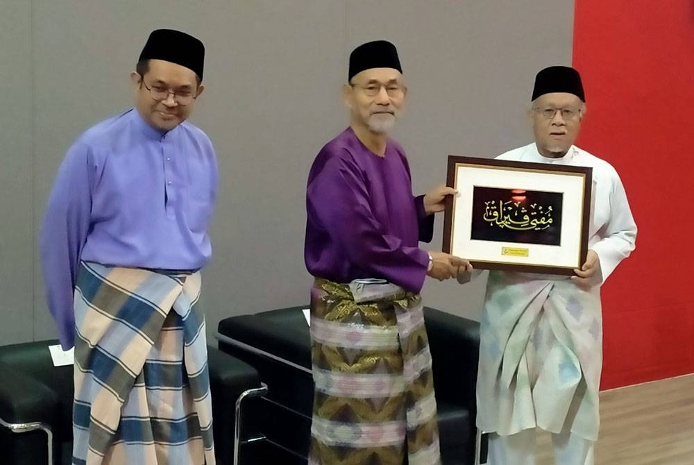 Wan Zahidi (kanan) menyampaikan cenderahati kepada Nooh (tengah) selepas menjadi panel program Liqa&#039; Fikri Bersama Pengerusi Muzakarah MKI dan Mufti Perak di Auditorium Universiti Sultan Azlan Shah di sini pada Jumaat.